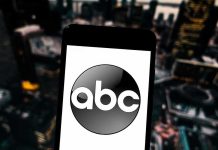 A smartphone displaying the ABC logo against an urban backdrop