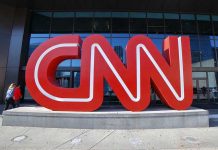 CNN Under Fire for Smearing Large red CNN sign outside building entrance.