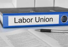 Blue binder labeled Labor Union beside papers and pen.