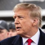 Trump’s ‘Board of Peace’ Threatens UN Man in suit and red tie speaking outside.