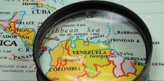 U.S. Forces Capture Venezuelan Dictator Magnifying glass focusing on Venezuela and Colombia on map.