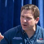 Man in Desantis for President shirt speaking.