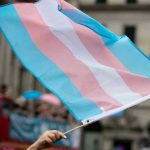 Gender Identity Claims Exposed: What’s the Limit? Transgender flag waving in a crowded street.