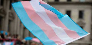 Gender Identity Claims Exposed: What’s the Limit? Transgender flag waving in a crowded street.