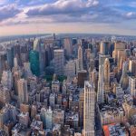 Aerial view of city with skyscrapers and cloudy sky.