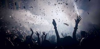 Crowd celebrating under confetti and bright lights.
