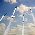 Multiple missiles launching into a cloudy sky