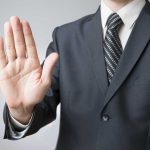 A man in a suit holding up his hand in a stop gesture