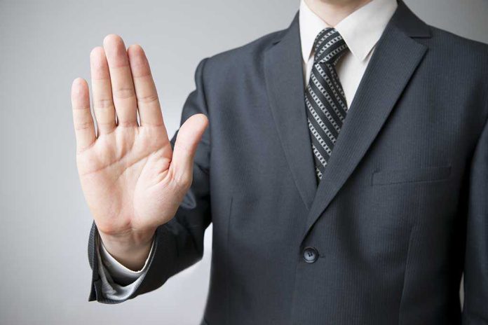 A man in a suit holding up his hand in a stop gesture