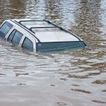 Raging Creek Traps Family – See Rescue! A partially submerged vehicle in floodwaters
