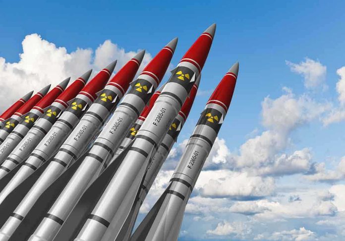 A row of military missiles with red tips and nuclear symbols against a blue sky