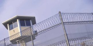 Masked Chaos Triggers Newark Lockdown Guard tower behind barbed wire fence in a prison.