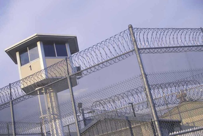 104591603 Guard tower behind barbed wire fence in a prison.