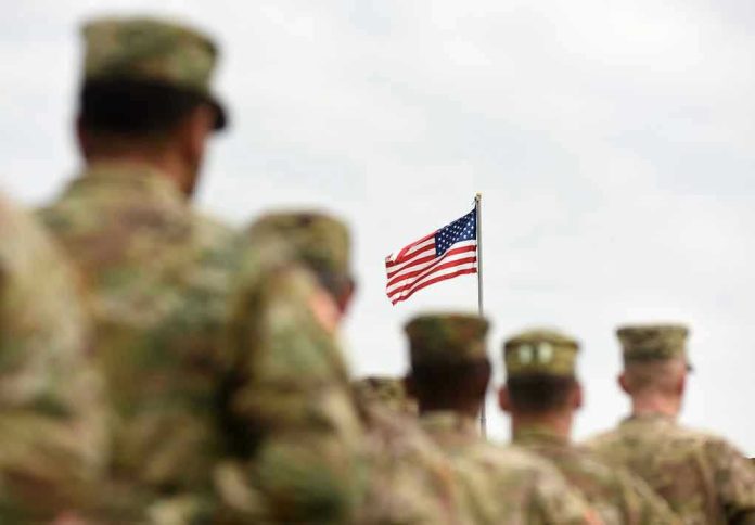 Soldiers in uniform standing, American flag in background.