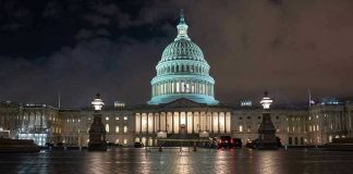 U.S. Capitol building illuminated at night with wet pavement.