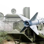 Military missile launcher with radar systems in a foggy field.