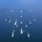 Aerial view of multiple naval ships operating in the ocean