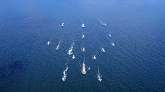 Aerial view of multiple naval ships operating in the ocean