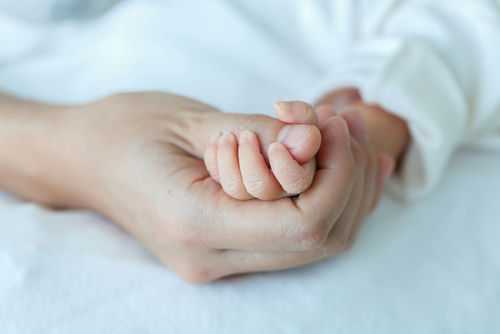 mother-and-baby294313661 Adult hand holding a babys hand tightly