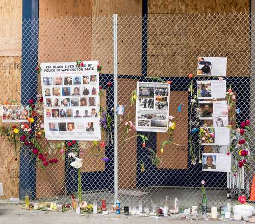 A memorial display with photos and flowers on a fence