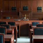 Viral Migrant Rape Claim Has No Public Record Empty courtroom with wooden furnishings and judges bench.