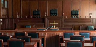 Viral Migrant Rape Claim Has No Public Record Empty courtroom with wooden furnishings and judges bench.