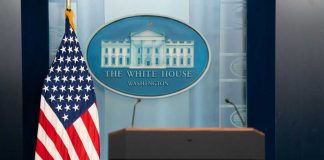 Podium with microphones in front of the White House seal and an American flag