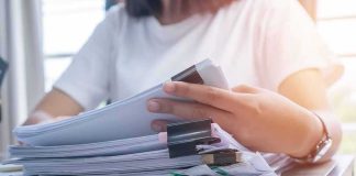 Court Twist Lets USPS Police Ballots Person organizing a stack of documents with binder clips