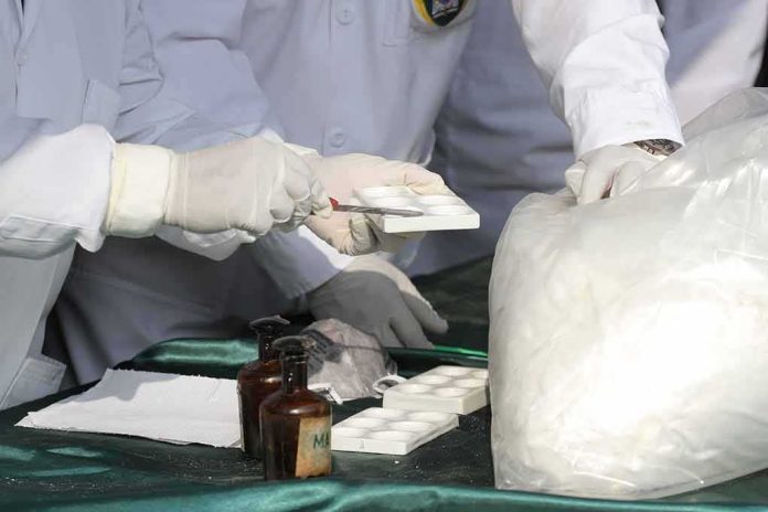 shutterstock_2040333971 Scientists in lab coats handling white powder sample with tools