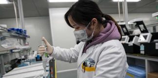Scientist in lab coat using a pipette