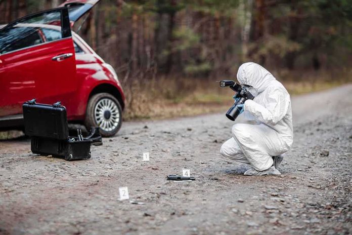 shutterstock_778440334 Forensic investigator photographing evidence near a red car on a rural road