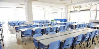 Empty cafeteria with rows of blue chairs and long tables