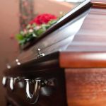 Near-Death Standoff: Moscow Blocks Mom Wooden casket with floral arrangement
