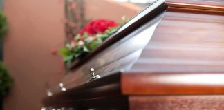 Near-Death Standoff: Moscow Blocks Mom Wooden casket with floral arrangement