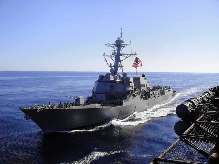 shutterstock_1250591794 naval destroyer sailing at sea with flag flying