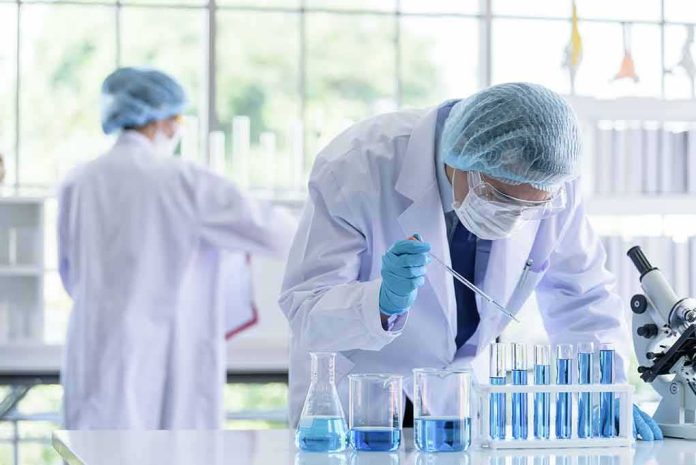 Scientist pipetting blue liquid into test tubes in a laboratory