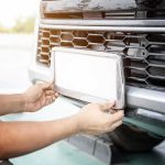 Police Snoop Tool Exposed — Is That Plate Yours? Person installing a car license plate on a front bumper