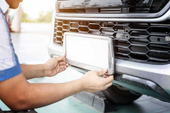 shutterstock_1628670280 Person installing a car license plate on a front bumper