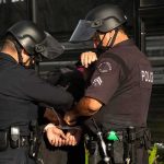 Police officers handcuff a person during an arrest