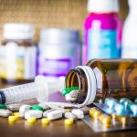 Funding Cutoff Hits Trans Kids—Hospitals Flinch Medicine pills and syringe on table with brown bottle