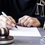 New Details About Former Marine Arrested on Trump Golf Course With Gun and Ammo Judge writing at desk with gavel and Lady Justice statue