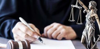 New Details About Former Marine Arrested on Trump Golf Course With Gun and Ammo Judge writing at desk with gavel and Lady Justice statue