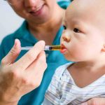 Clinic Language War Ignites Maine Firestorm Baby taking liquid medicine from an oral syringe held by an adult