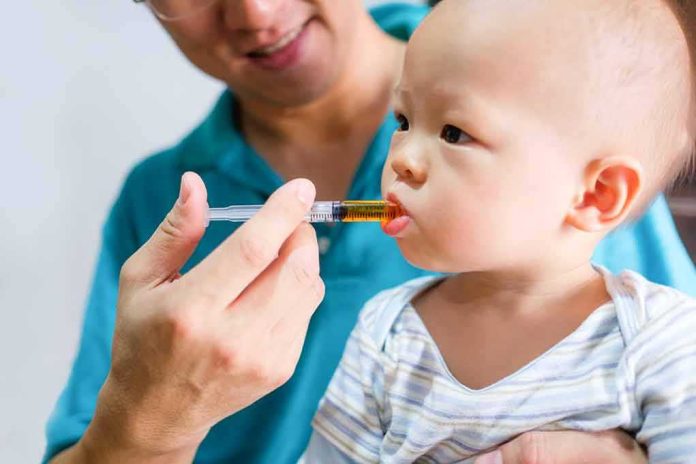 Baby taking liquid medicine from an oral syringe held by an adult