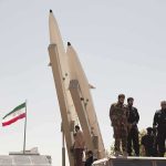 Negotiations? Or Just Stalling? soldiers stand beside large missiles at outdoor display