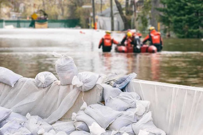 shutterstock_705371167 Sandbags stacked near a flooded street with rescue workers in a boat