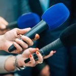 Reporters holding colorful microphones