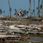 Tilted house amid widespread coastal destruction with palm trees