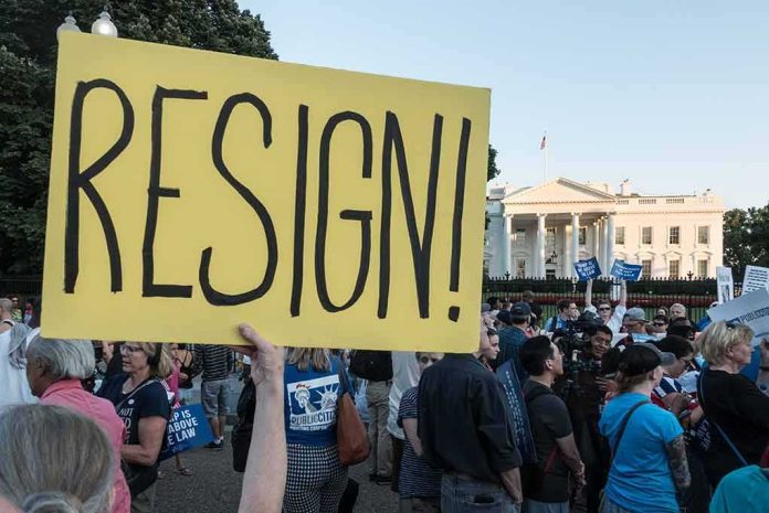 Merle Wasmuth at protest holding large yellow 'RESIGN!' sign near the White House
