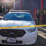 Aaron Guiel near police car behind yellow caution tape